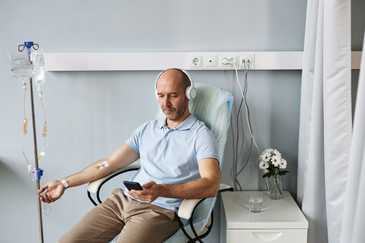 Minimal adult man with headphones during IV drip treatment in clinic