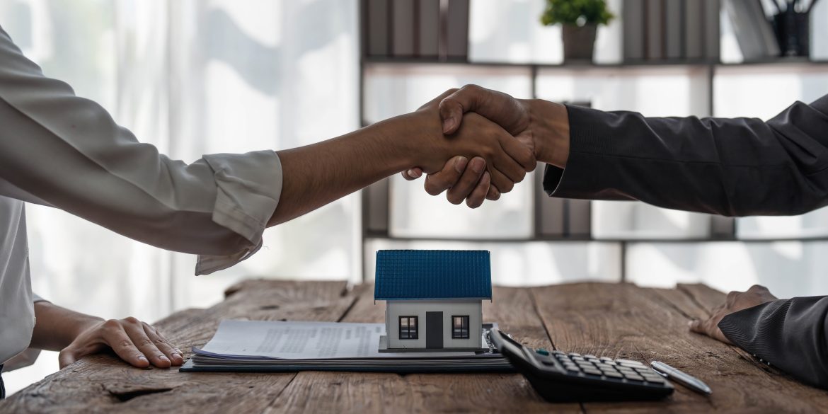 Real estate agent or realtor shakes hands with her client after making the deal in the office. cropped shot
