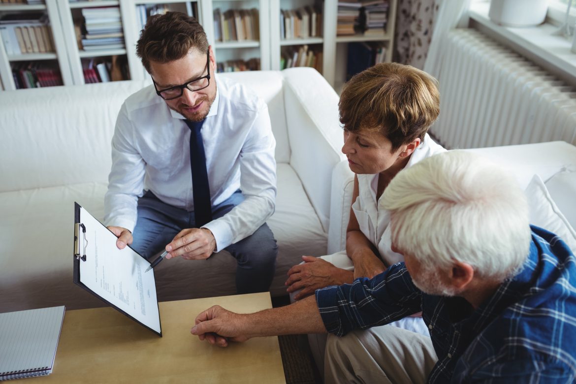 Senior couple planning their investments with financial advisor in living room