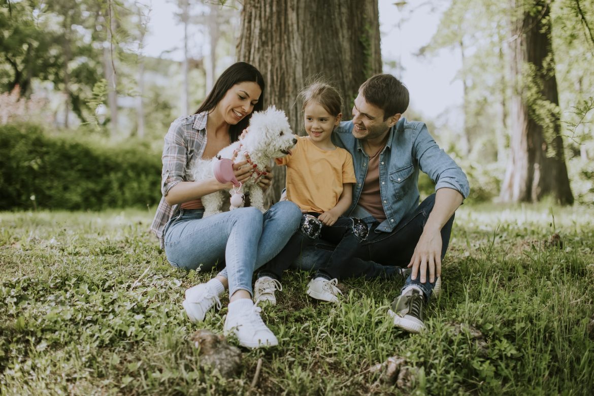 Happy family with cute bichon dog in the park