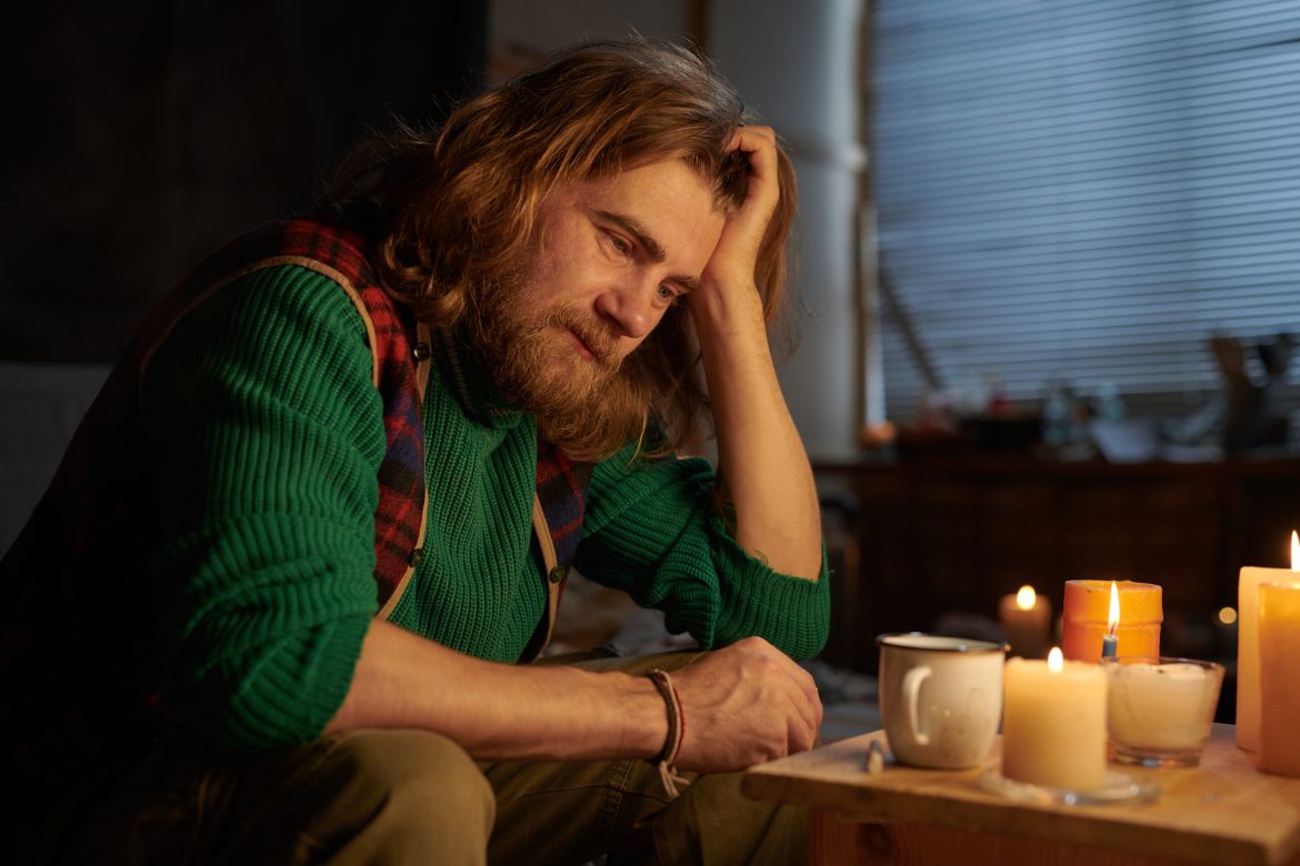 Man Sitting Alone Reflecting by Candlelit Table